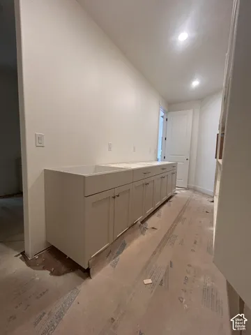 Built-in cabinetry featuring shaker-style doors, stone-surface countertops, and an integrated drop-in sink with recessed lighting