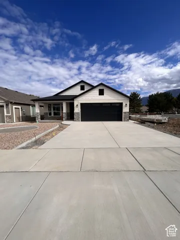Single-story exterior featuring a two-car garage, horizontal siding, stone veneer accents, and a concrete driveway