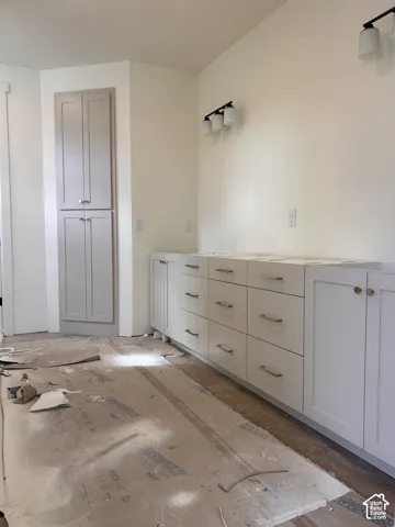 Built-in cabinetry featuring shaker-style doors, matte-finish hardware, a tall floor-to-ceiling storage unit, and multi-light wall fixtures