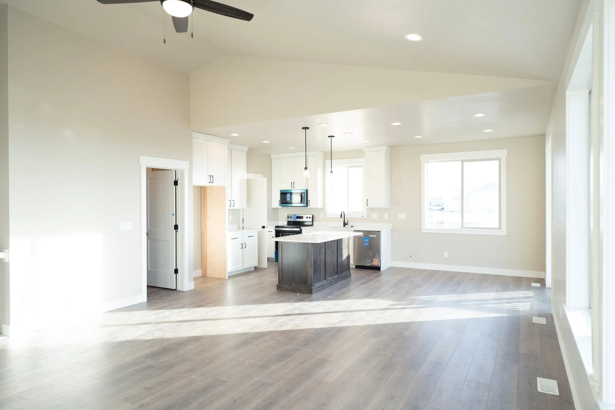 Kitchen featuring lofted ceiling, pendant lighting, appliances with stainless steel finishes, white cabinetry, and a center island
