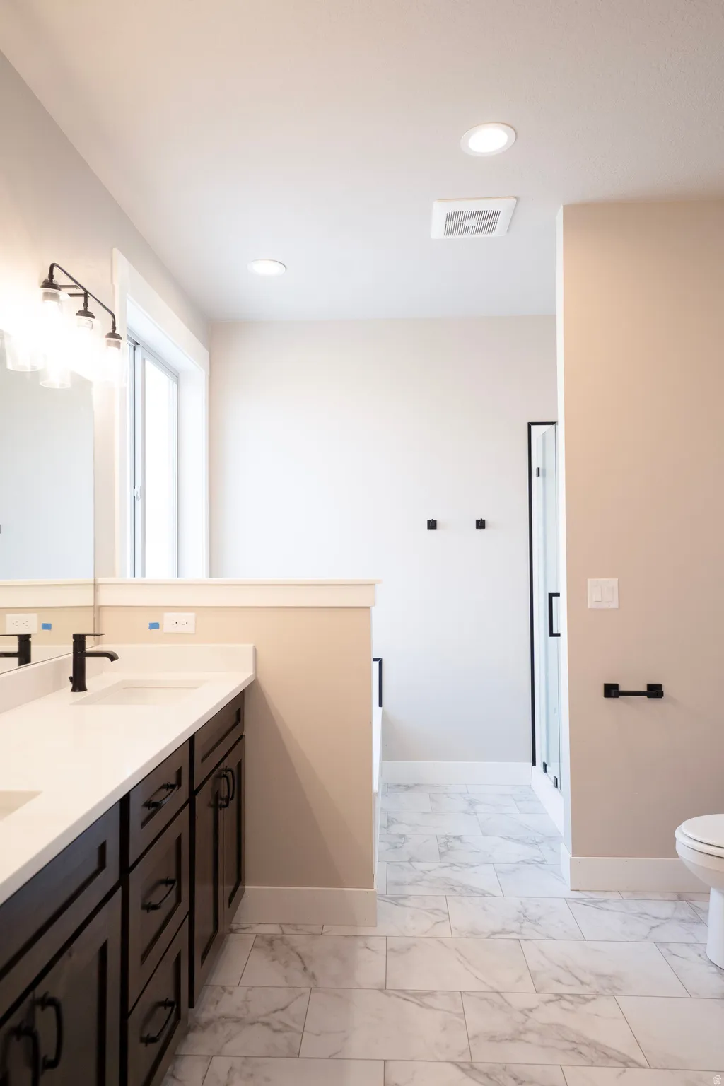 Full bathroom featuring double vanity, light marble finish flooring, and recessed lighting