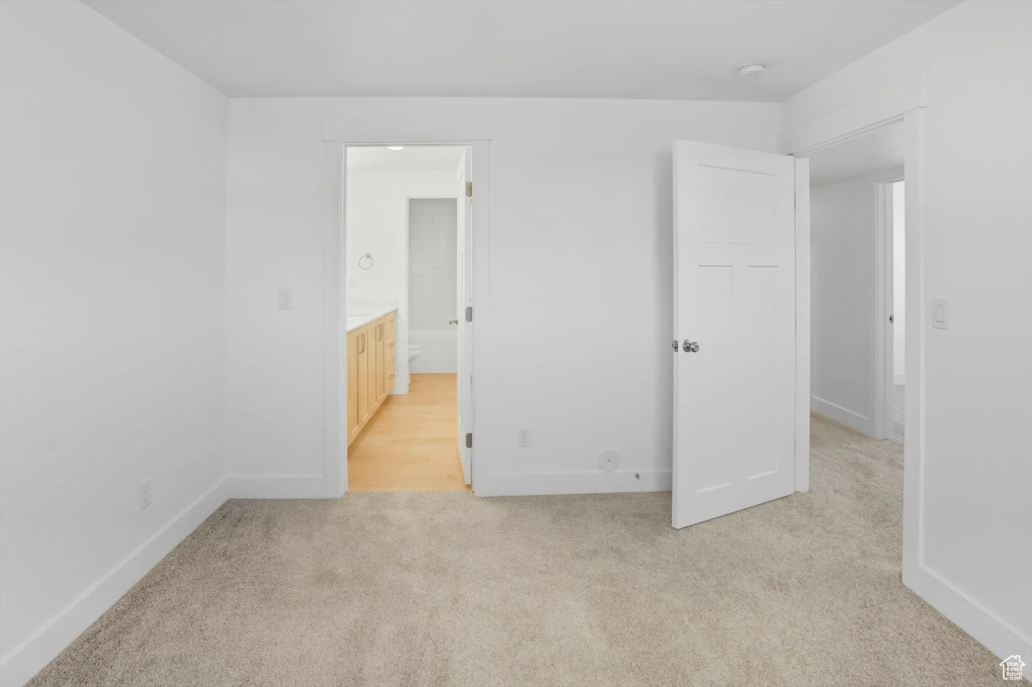 Unfurnished bedroom featuring connected bathroom and light carpet