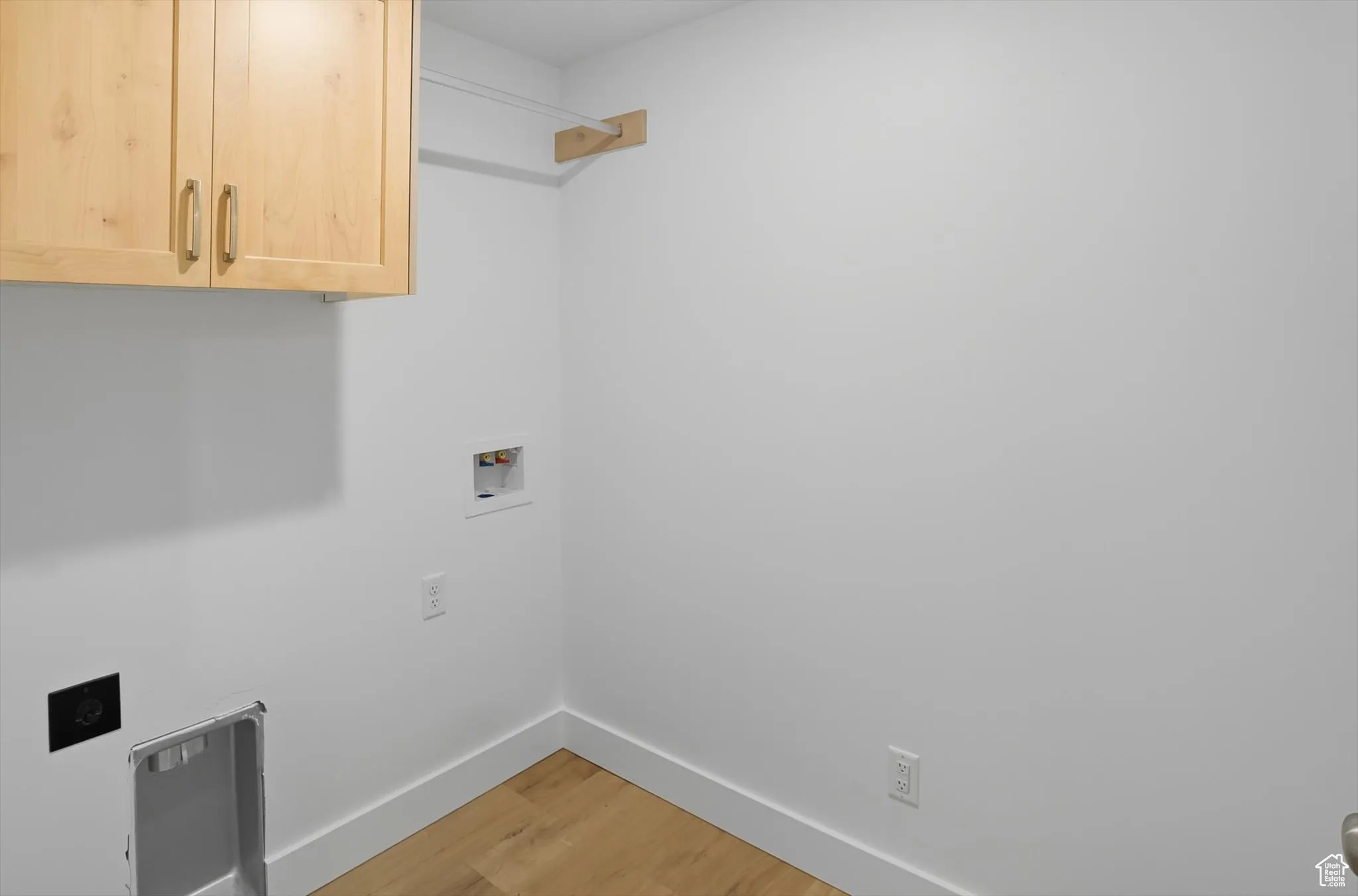 Washroom with light wood finished floors, washer hookup, cabinet space, and electric dryer hookup