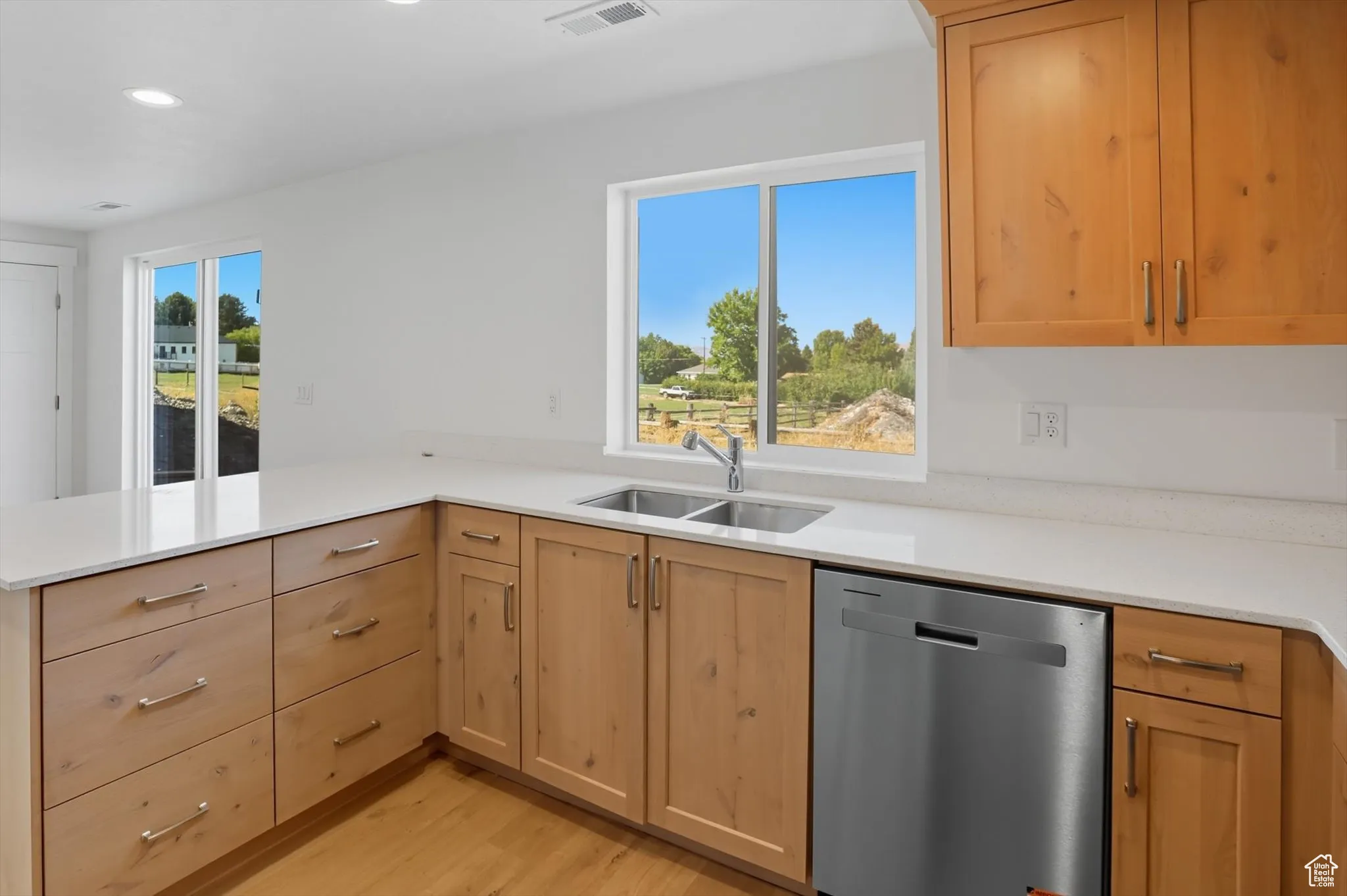 Kitchen with dishwasher, light wood-type flooring, light stone countertops, recessed lighting, and a peninsula
