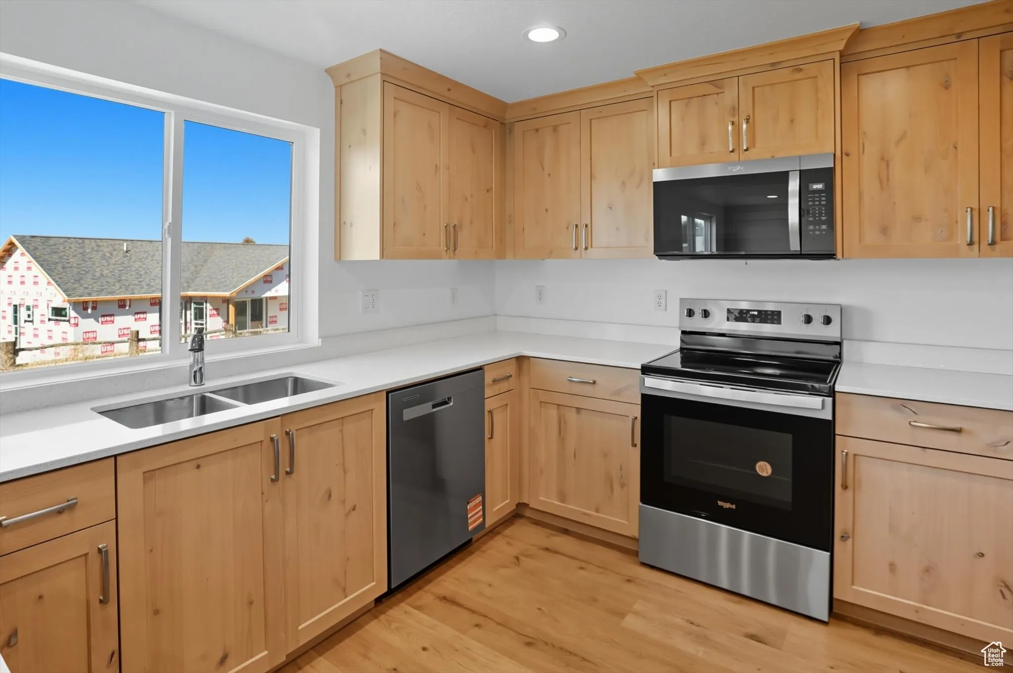 Kitchen with light brown cabinets, appliances with stainless steel finishes, light wood-type flooring, and recessed lighting