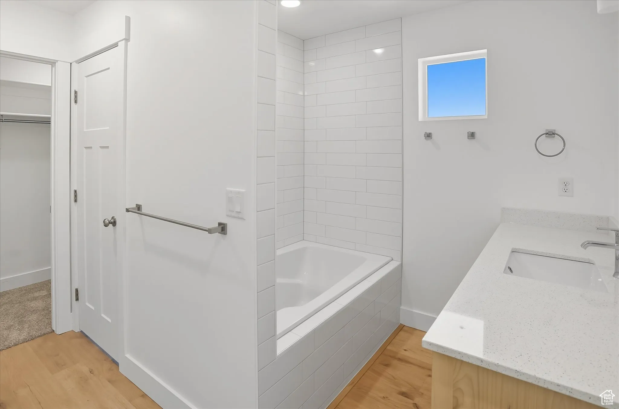Bathroom featuring light wood-style flooring, vanity, a walk in closet, and tiled shower / bath