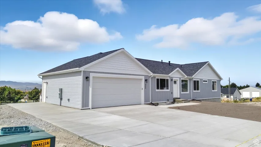 Ranch-style house featuring a shingled roof, concrete driveway, and a garage