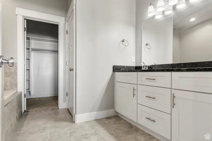 Bathroom with a spacious closet, vanity, and light tile patterned floors