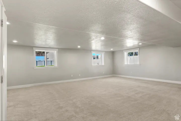 Basement featuring light colored carpet, recessed lighting, and a textured ceiling
