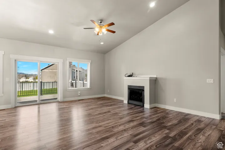 Unfurnished living room featuring a fireplace, wood finished floors, ceiling fan, lofted ceiling, and recessed lighting