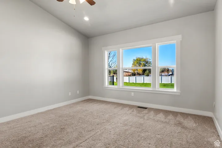 Carpeted bedroom with a ceiling fan and lofted ceiling