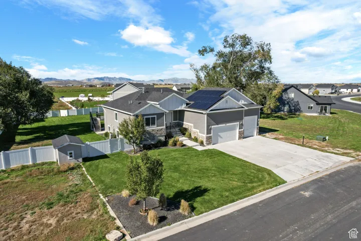 View of front of home with stone siding, roof mounted solar panels, concrete driveway, board and batten siding, and a mountain view