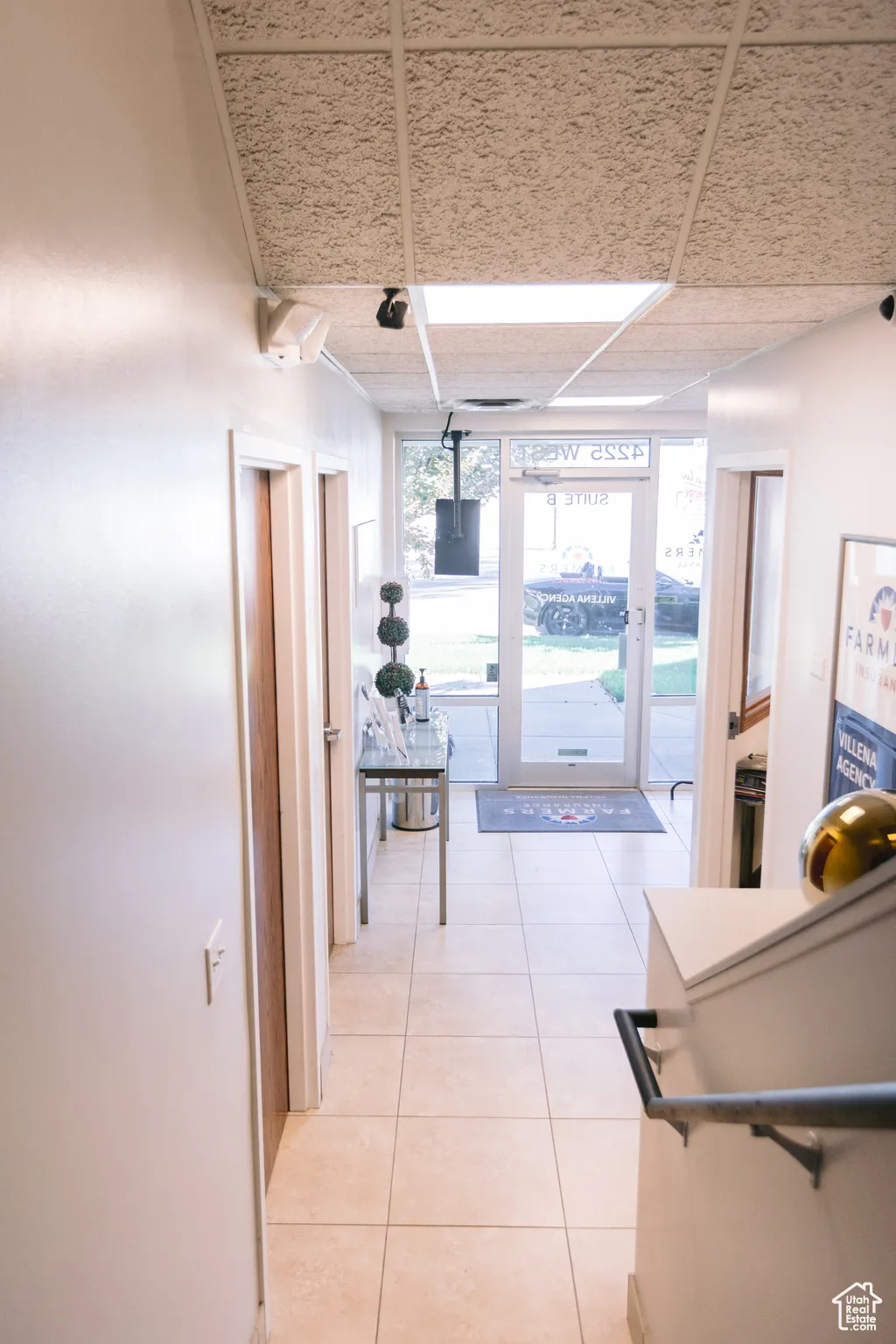 Corridor featuring a paneled ceiling and light tile patterned floors
