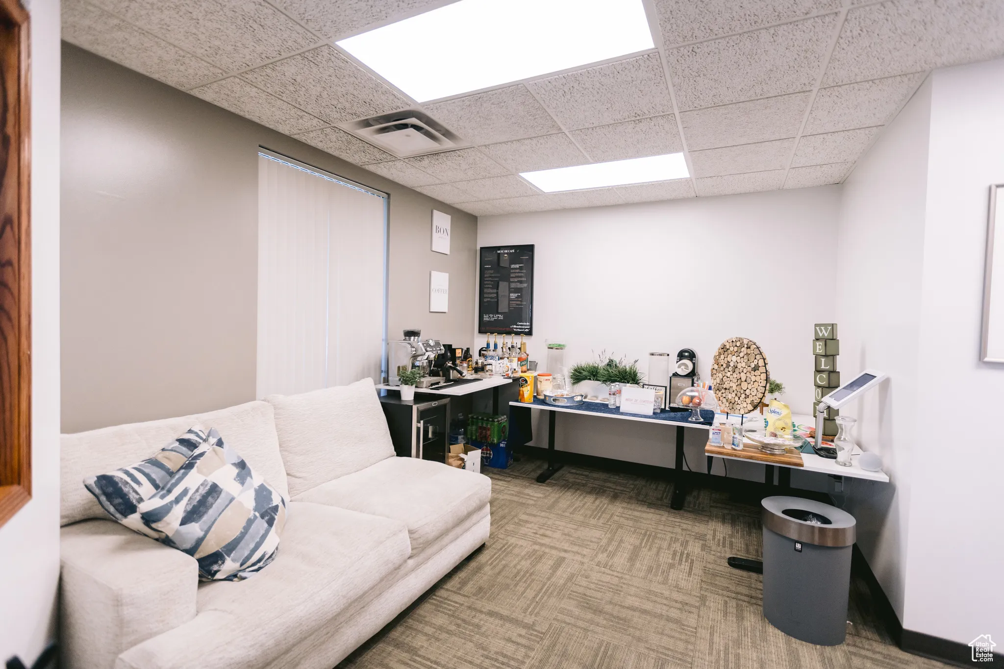 Living area with a paneled ceiling and carpet flooring
