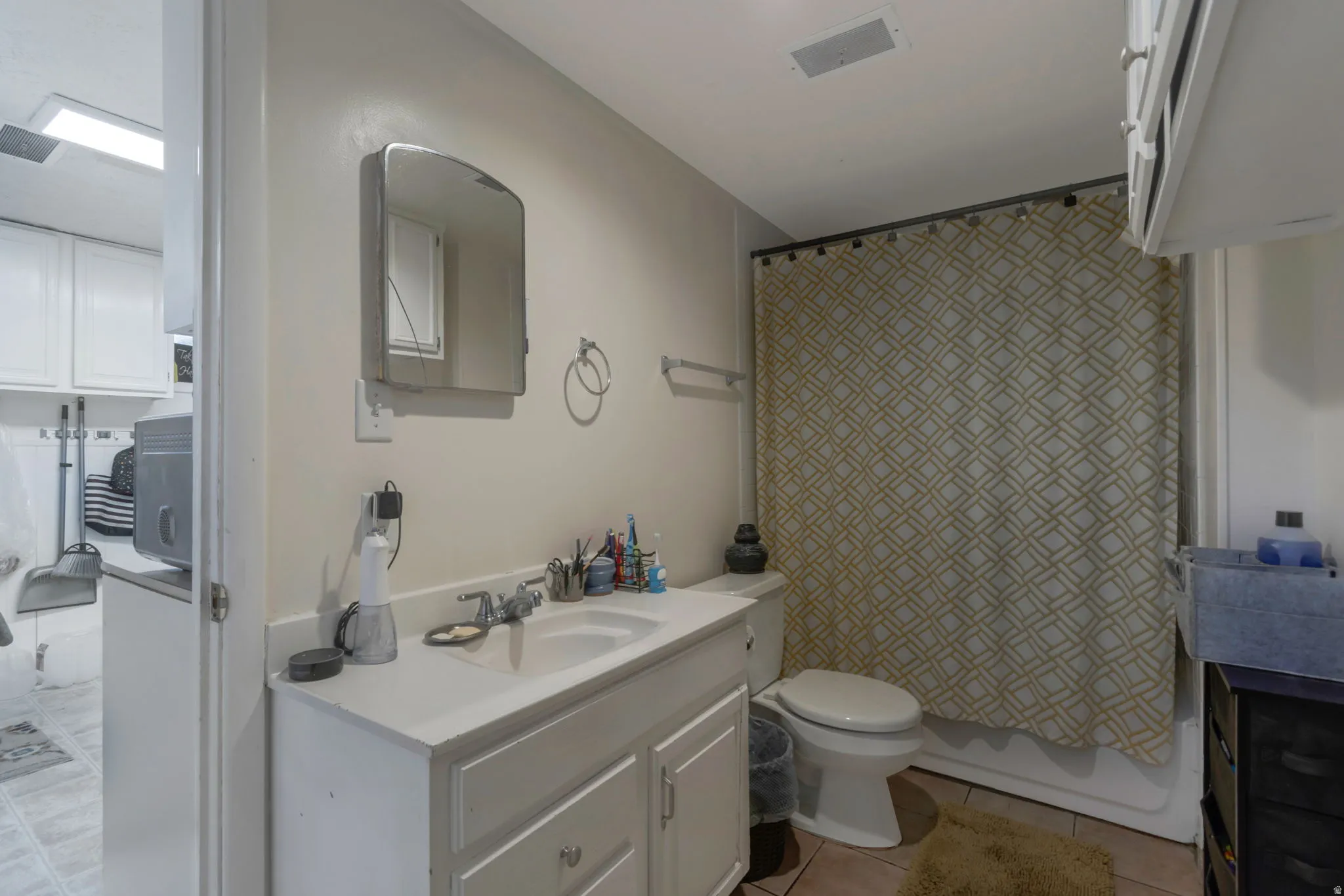 Basement Full bath with vanity, light tile patterned floors, and shower / bath combo
