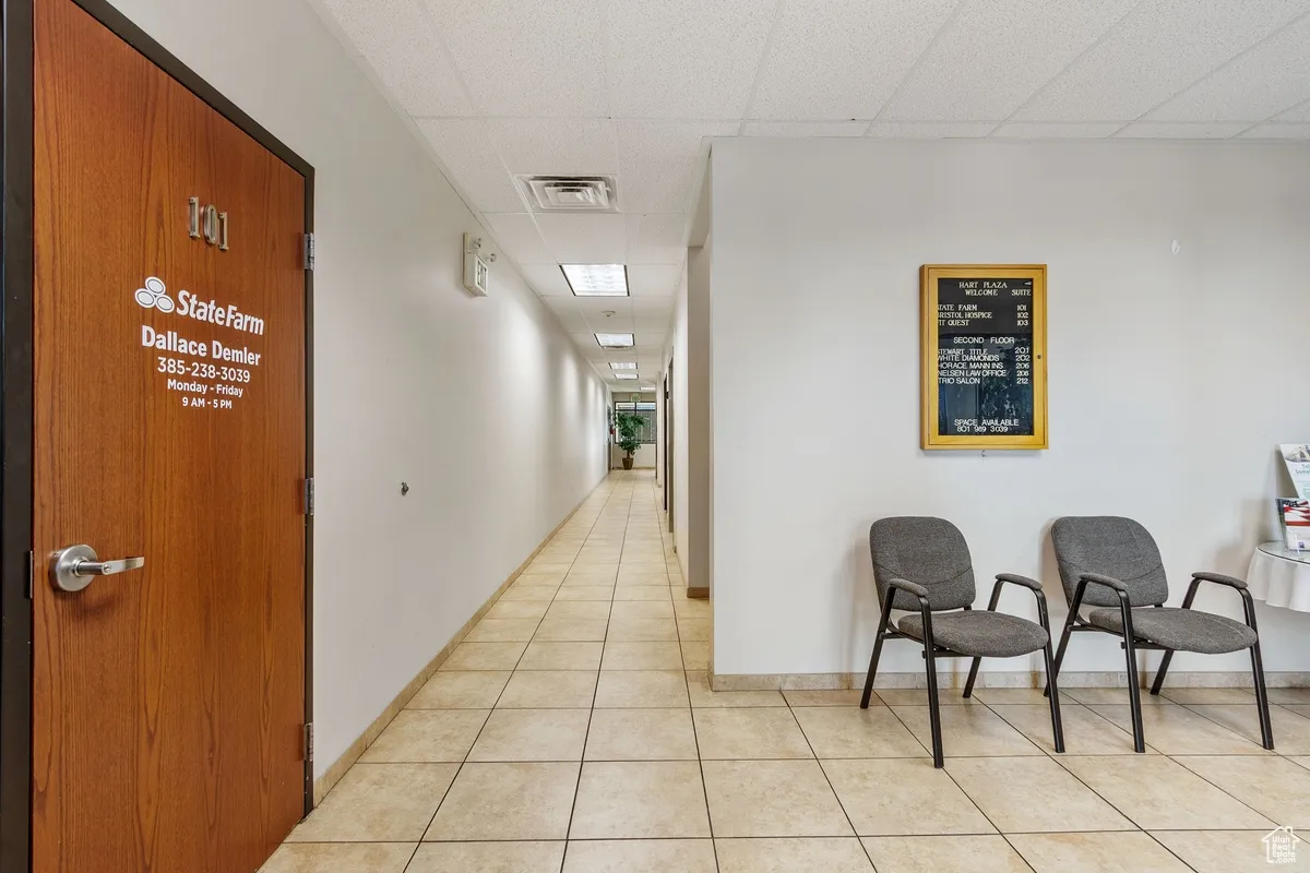Corridor featuring a paneled ceiling and light tile patterned floors