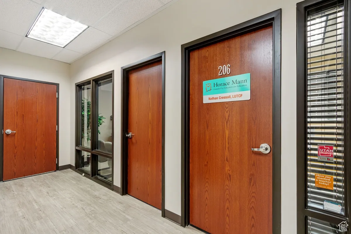 Corridor featuring a paneled ceiling and light wood-style floors
