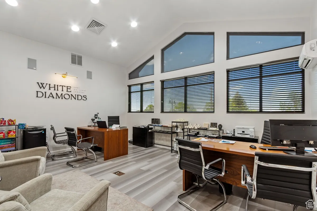 Office area with high vaulted ceiling, a wall mounted air conditioner, and recessed lighting