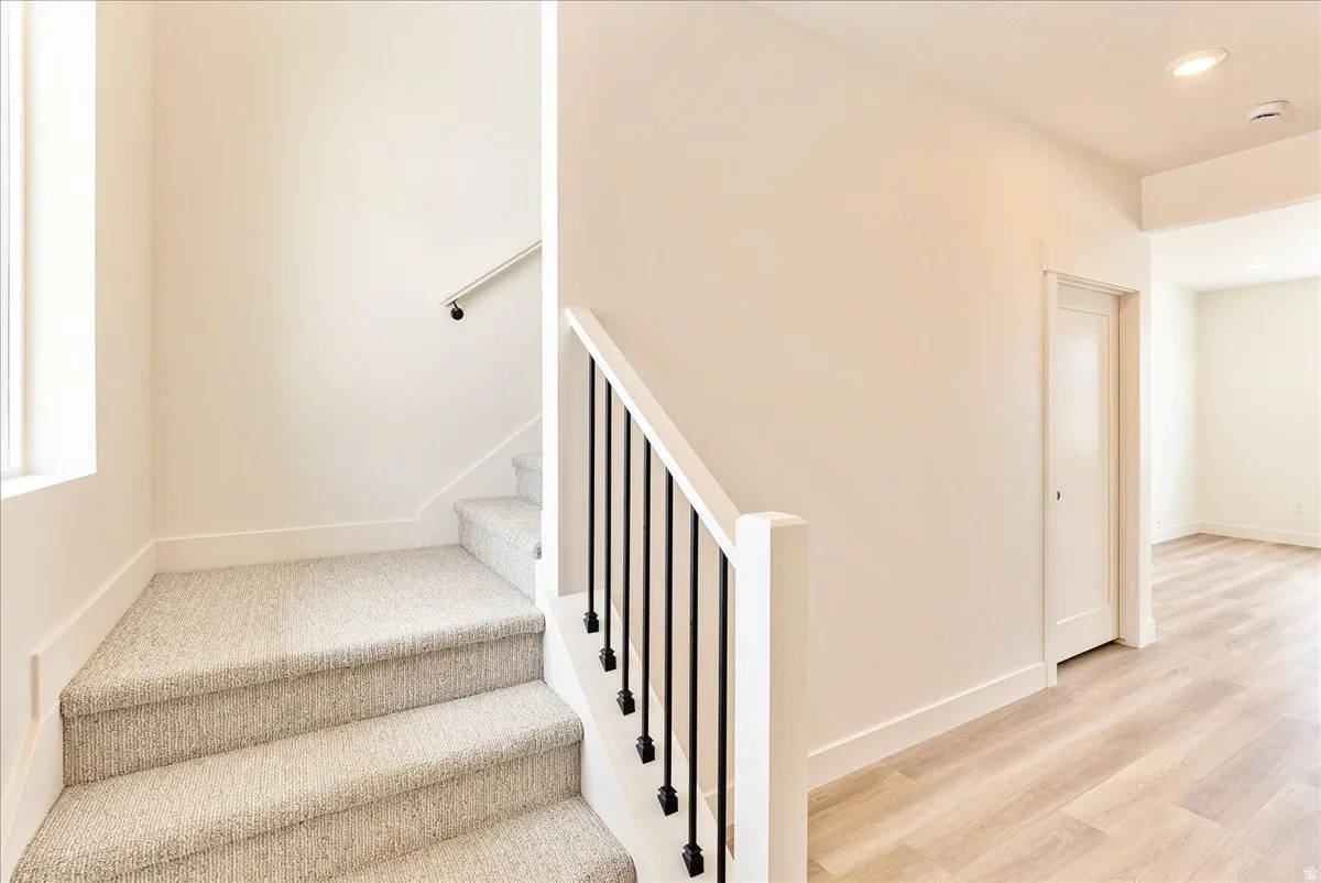 Stairs with wood finished floors and recessed lighting