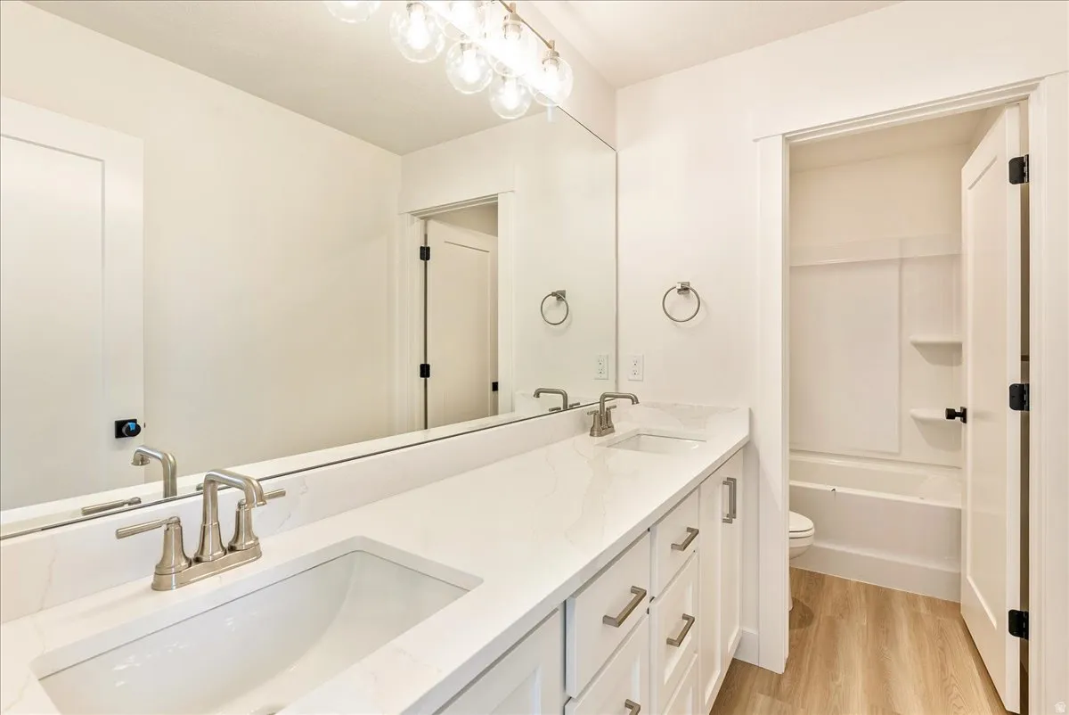 Bathroom featuring double vanity, light wood-style floors, and  shower combination