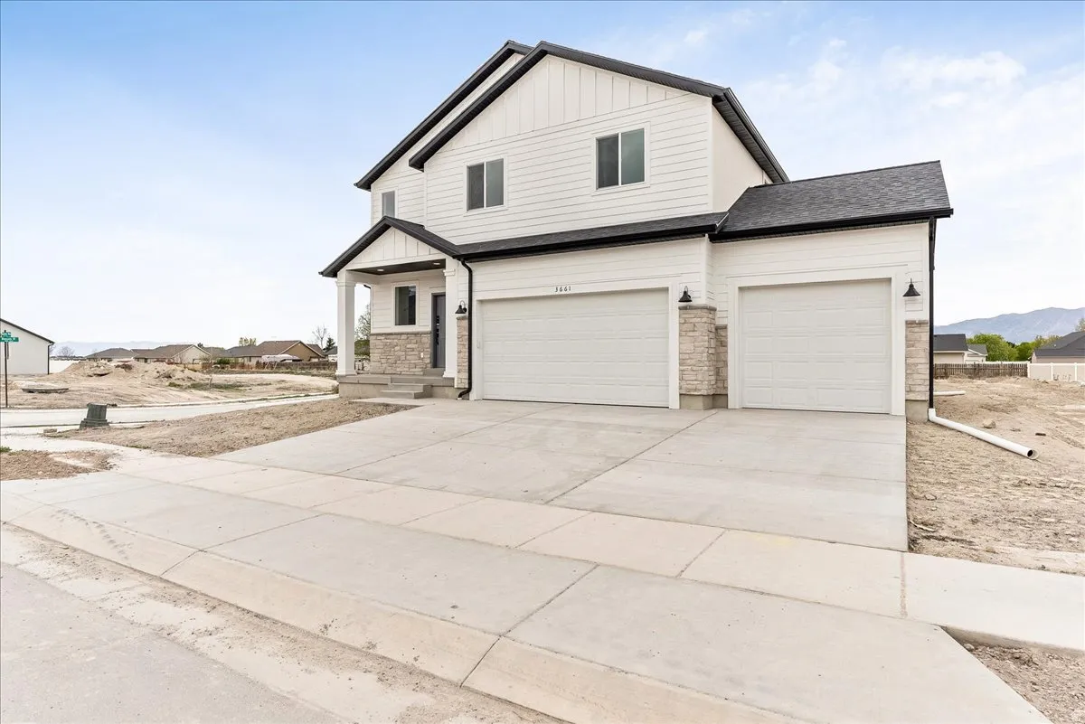 View of front of house featuring concrete driveway, board and batten siding, an attached garage, and stone siding