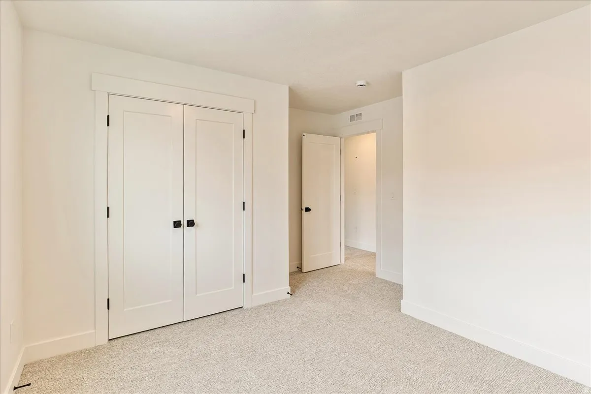Unfurnished bedroom with light colored carpet and a closet