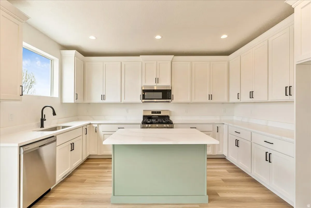 Dual tone kitchen featuring a center island, stainless steel appliances, recessed lighting, light stone counters, and light wood-style flooring