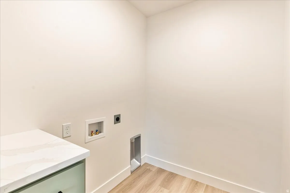 Laundry area with electric dryer hookup, light wood-type flooring, and washer hookup