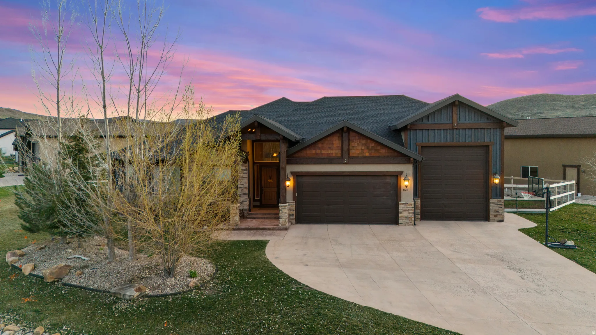 Craftsman-style home featuring a garage, concrete driveway, stone siding, and a yard
