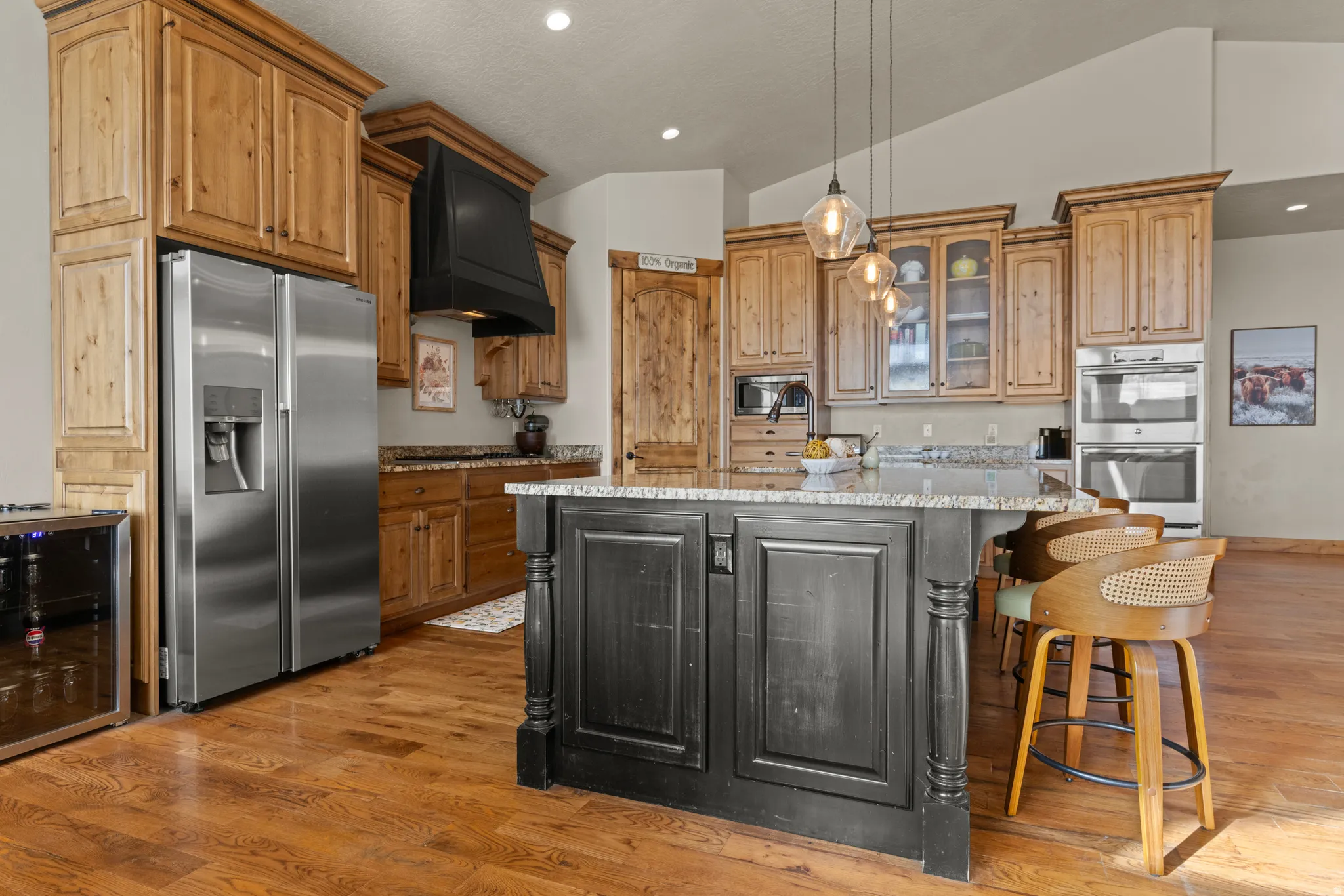 Kitchen featuring lofted ceiling, wine cooler, dual tone cabinetry, stainless steel appliances, and a center island