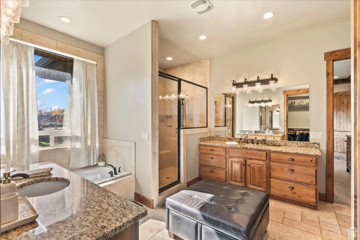 Primary ensuite; Bathroom with two vanities, a garden tub, a shower stall, recessed lighting, and stone tile floors