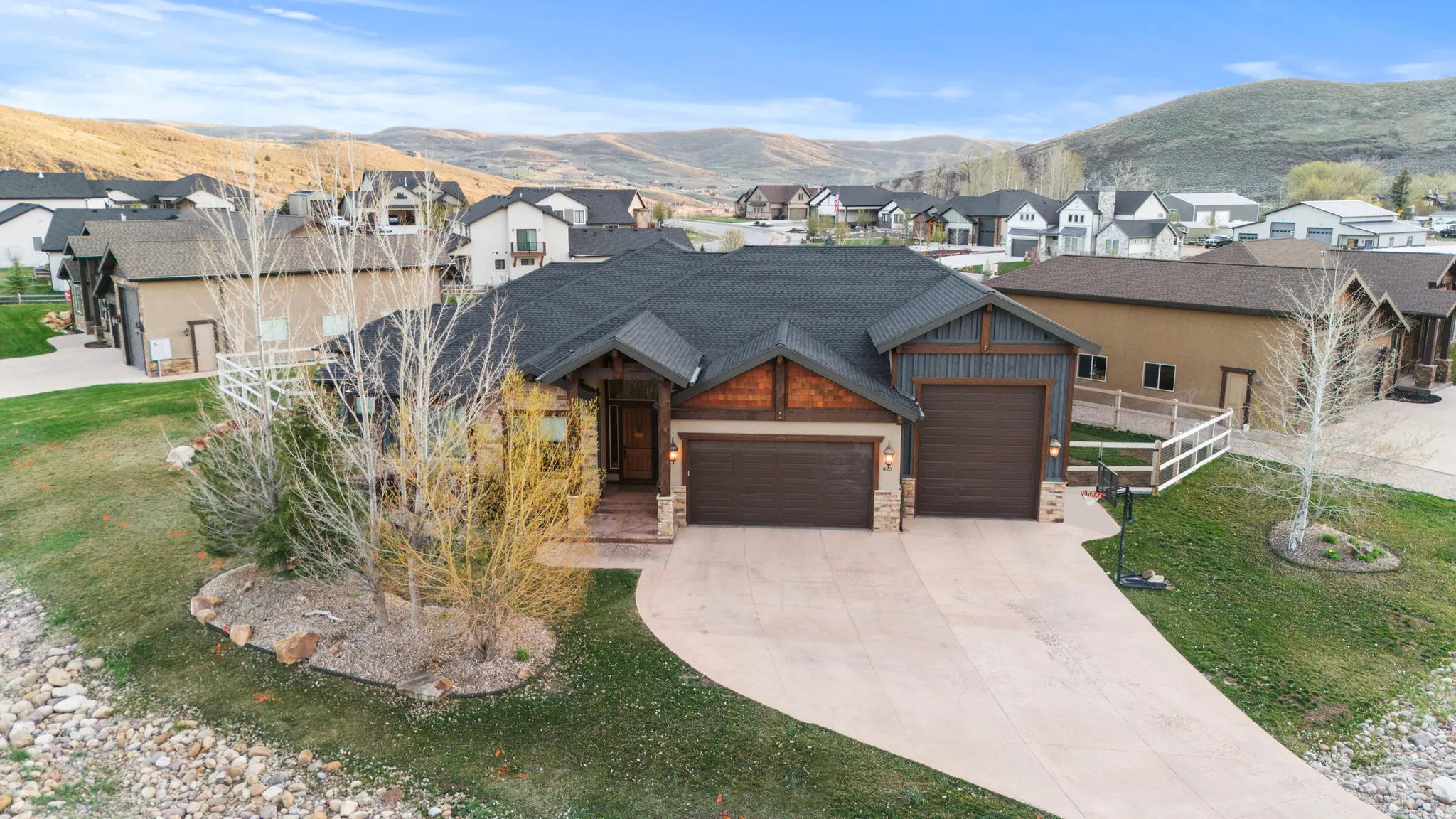 View of front of house featuring an attached garage, stone siding, a mountain view, driveway, and a residential view