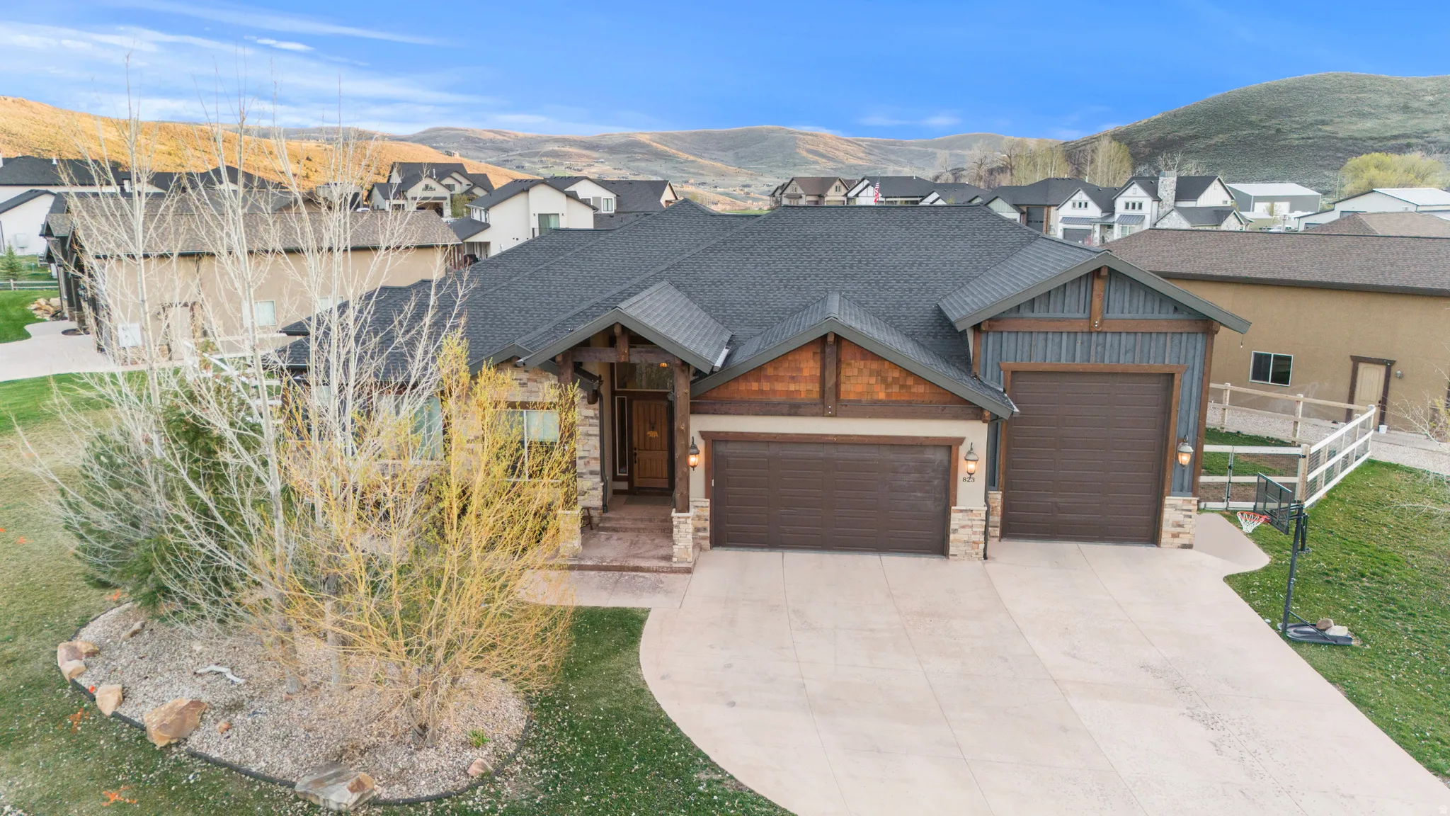 View of front of home with an attached garage, a mountain view, stone siding, and concrete driveway