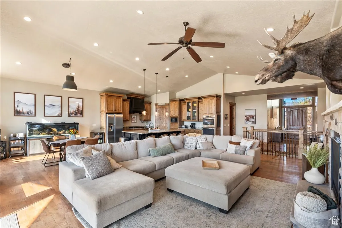 Living room featuring light wood-type flooring, a fireplace, ceiling fan, recessed lighting, and high vaulted ceiling