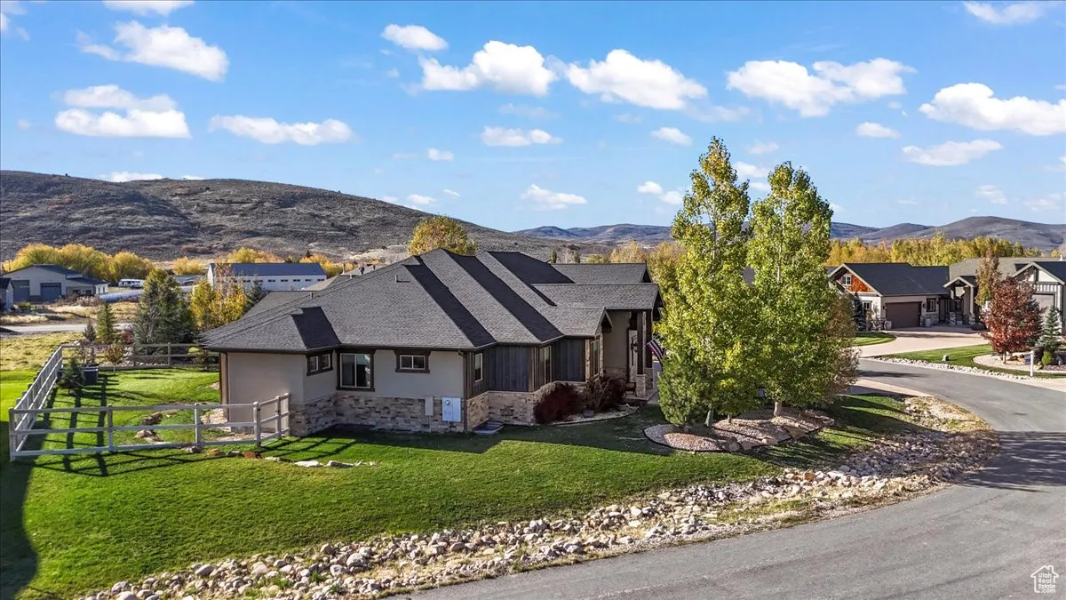 View of front of property with stone siding, a mountain view, stucco siding, and driveway