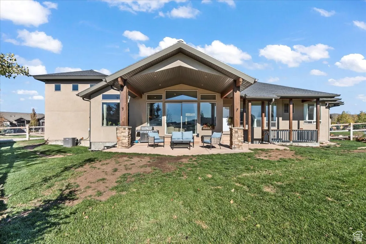 Rear view of property featuring stucco siding, a patio area, outdoor lounge area, and stone siding