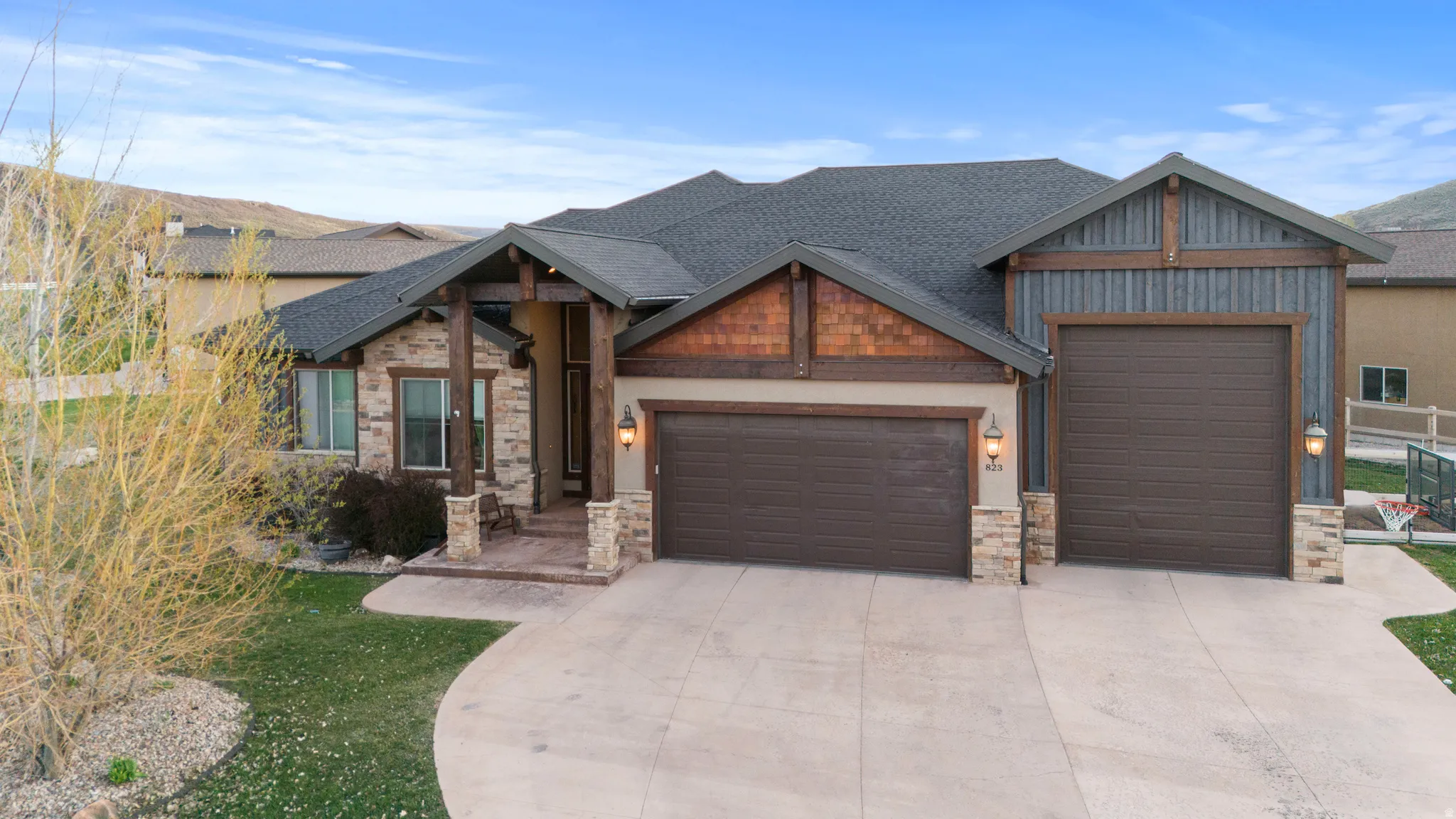 Craftsman-style house with a garage, concrete driveway, a shingled roof, and stone siding
