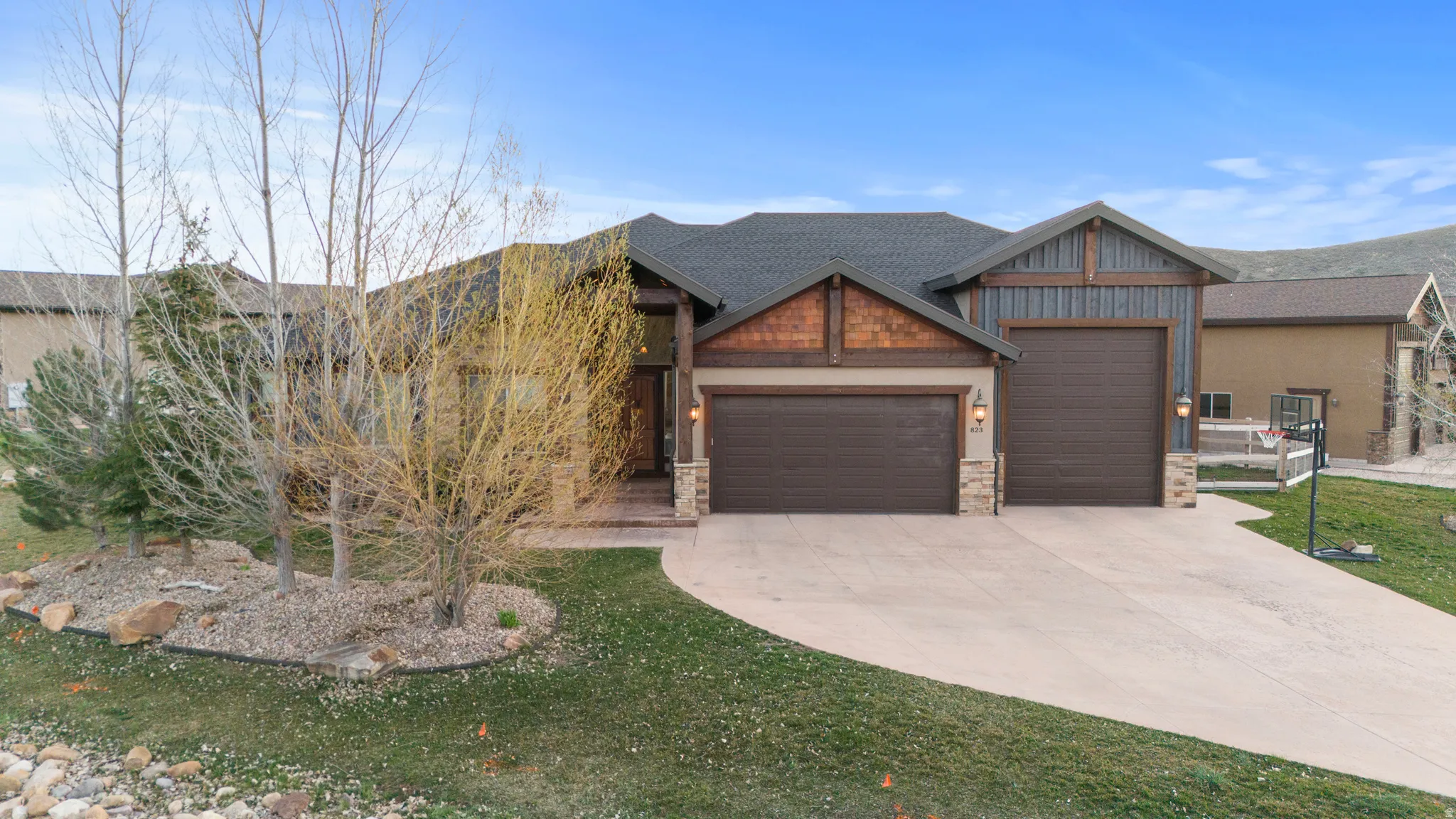 Craftsman inspired home with a garage, driveway, stone siding, and a shingled roof