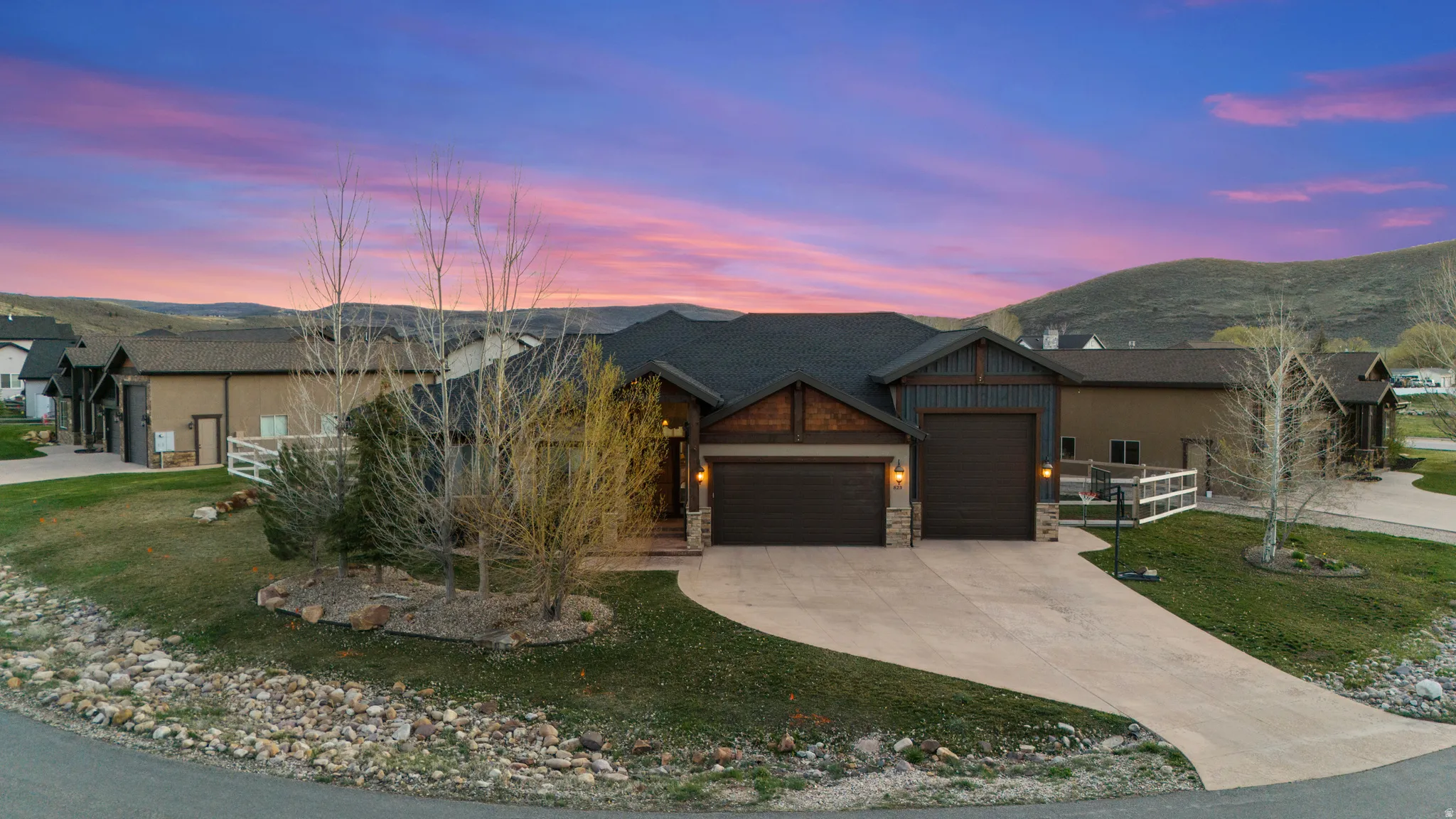 Craftsman-style home featuring a garage, stone siding, a mountain view, driveway, and a front lawn