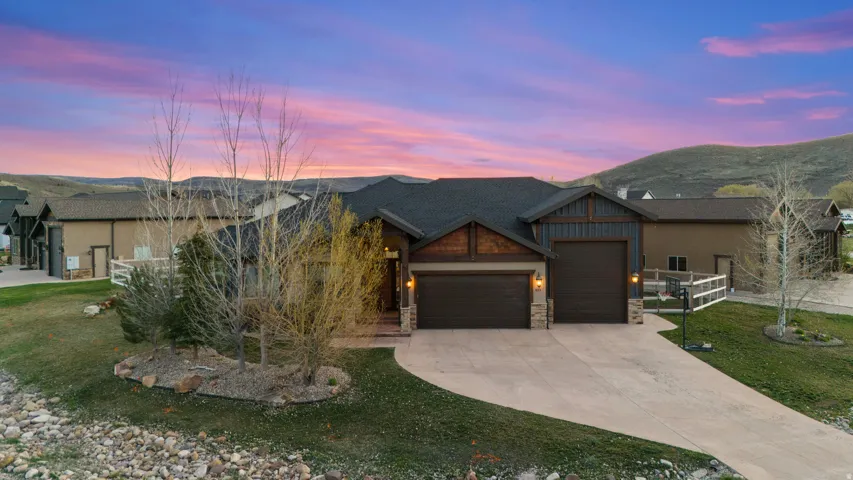 Craftsman inspired home with an attached garage, stone siding, driveway, a front lawn, and a mountain view