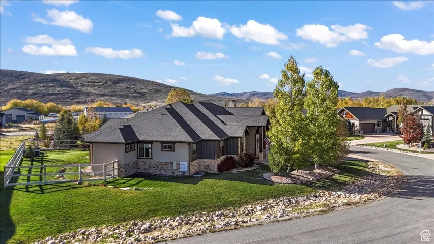 View of front of property with stone siding, a mountain view, stucco siding, and driveway