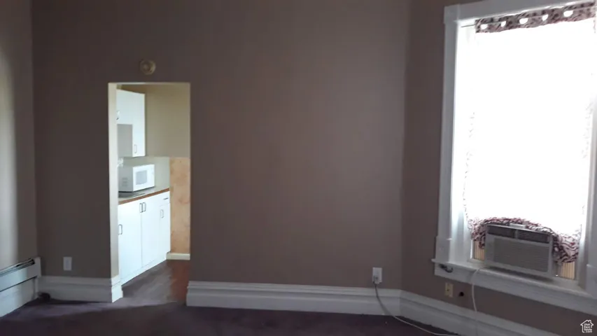 Unfurnished room with cooling unit and a baseboard heating unit