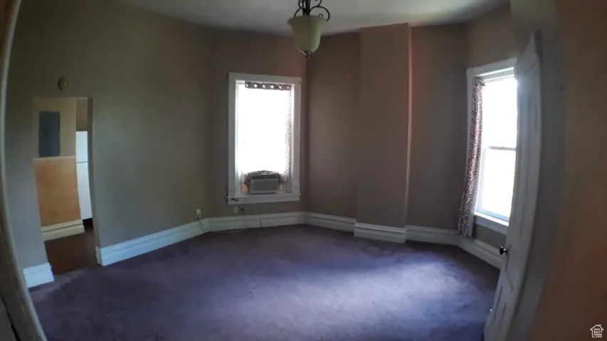 Unfurnished room with dark colored carpet and plenty of natural light