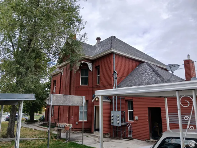 Back of property featuring a shingled roof and a chimney
