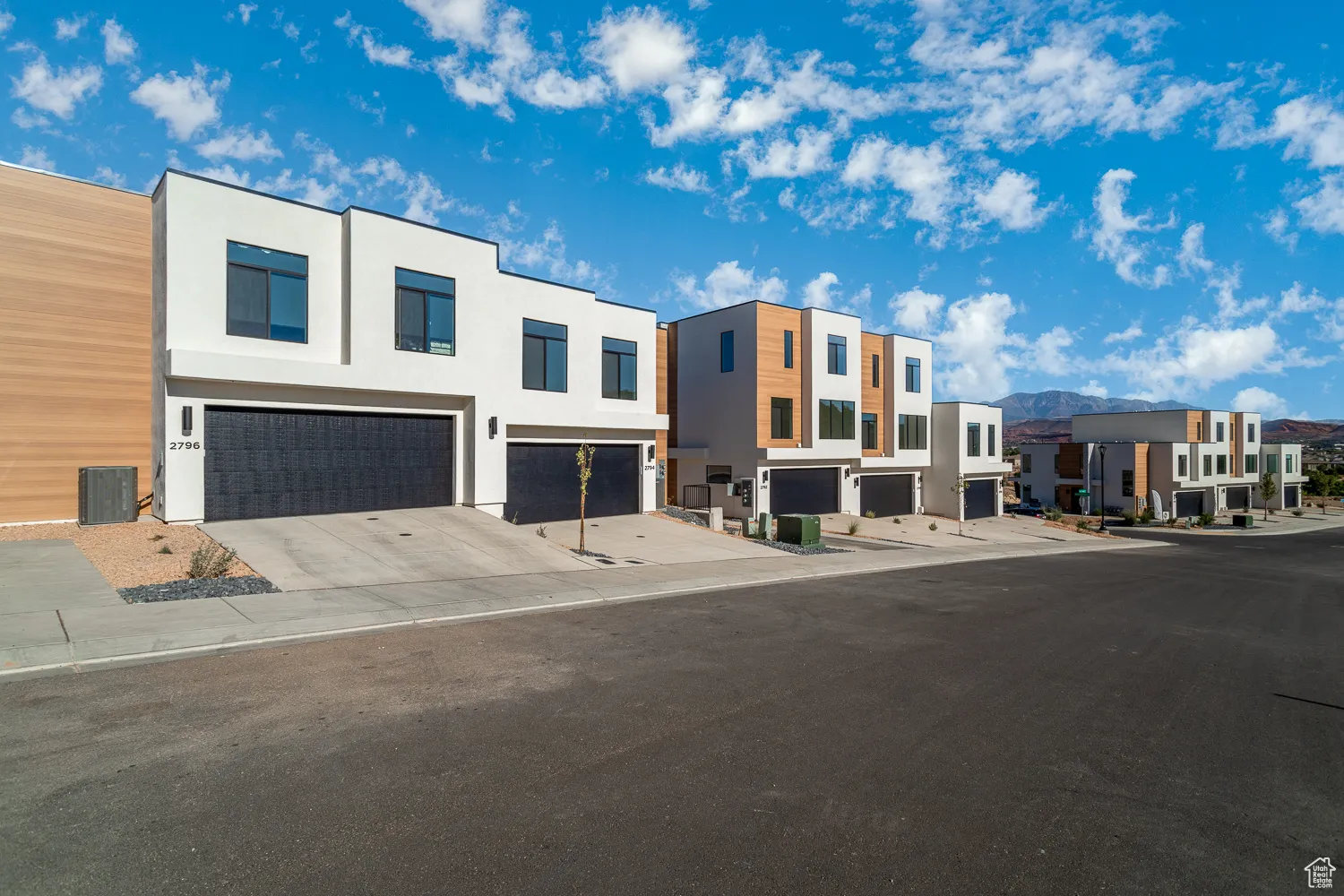 View of front of home with a residential view, stucco siding, an attached garage, driveway, and a mountain view