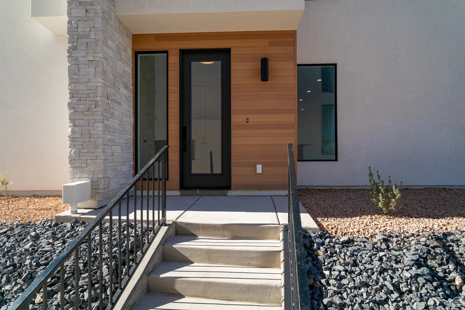 Property entrance with stucco siding, stone siding, and covered porch