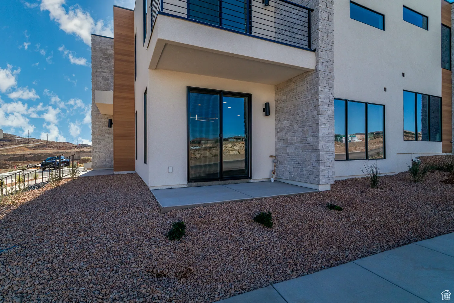 Entrance to property with stone siding, stucco siding, and a patio area