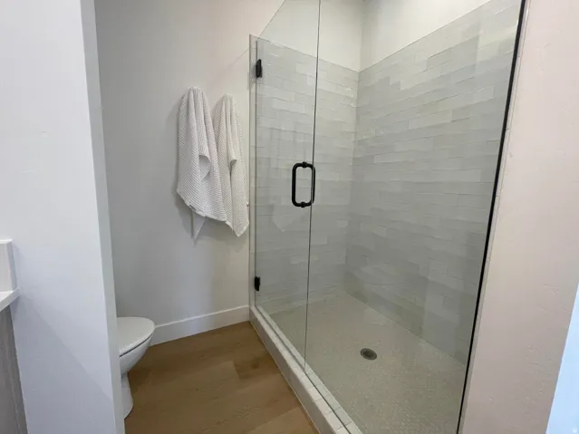 Glass-enclosed shower with matte black hardware, horizontal subway tile, and mosaic tile flooring