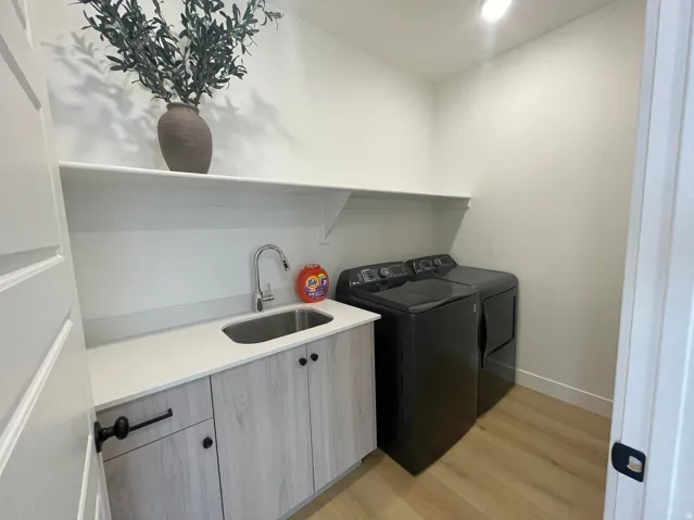 Laundry area featuring a built-in countertop, undermount sink, and wood-finish cabinetry