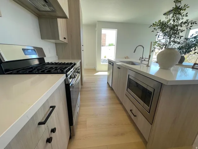 Kitchen featuring wood-finish cabinetry, white countertops, stainless steel appliances, and wood-finish flooring